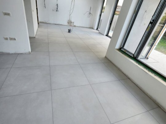 A spacious and modern open-plan kitchen and hall in Dublin, showcasing a flawless installation of large, polished cream-colored floor tiles by RCTiling.