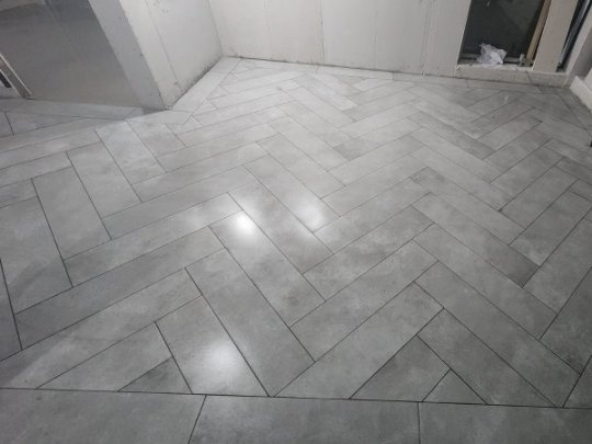 Newly installed grey rectangular tiles in a classic herringbone pattern on a floor, showcasing a professional installation by RCTiling Dublin.