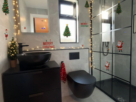 A modern bathroom floor featuring grey tiles in a herringbone pattern, styled with subtle holiday accents to demonstrate a festive transformation by RCTiling Dublin.