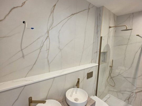 A clean, professionally installed herringbone tile floor in a modern bathroom, showcasing a hygienic and easy-to-clean surface by RCTiling Dublin.