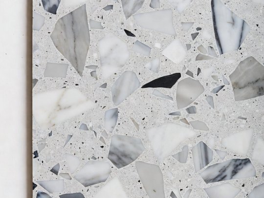 A high-quality sample slab of modern light grey terrazzo tiling featuring large white and dark grey marble aggregate pieces.
