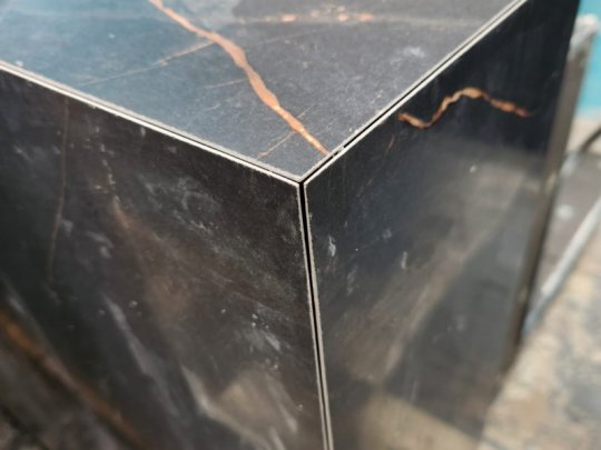 Polished black marble block with copper veining displayed in a workshop setting.