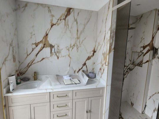 Luxury bathroom with marble-effect porcelain tiles, bespoke vanity unit, gold fixtures, and a modern walk-in shower in a high-end Dublin home.