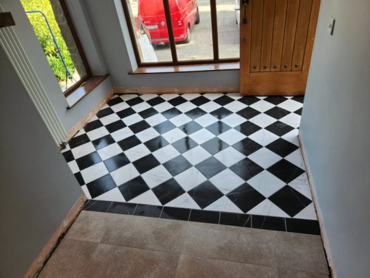 Black and white checkerboard porcelain tile floor installed in a family home entrance hallway with durable, easy-to-clean surface.