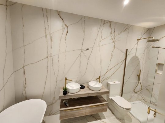Large format marble-effect porcelain tiles installed in a modern Dublin bathroom with a perfectly levelled wall and floor finish.