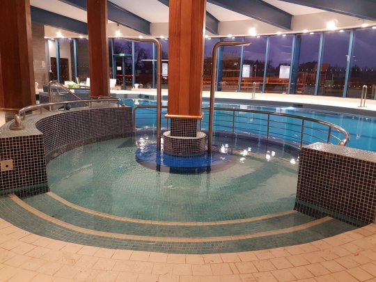 indoor spa pool with steps, wooden columns and panoramic windows