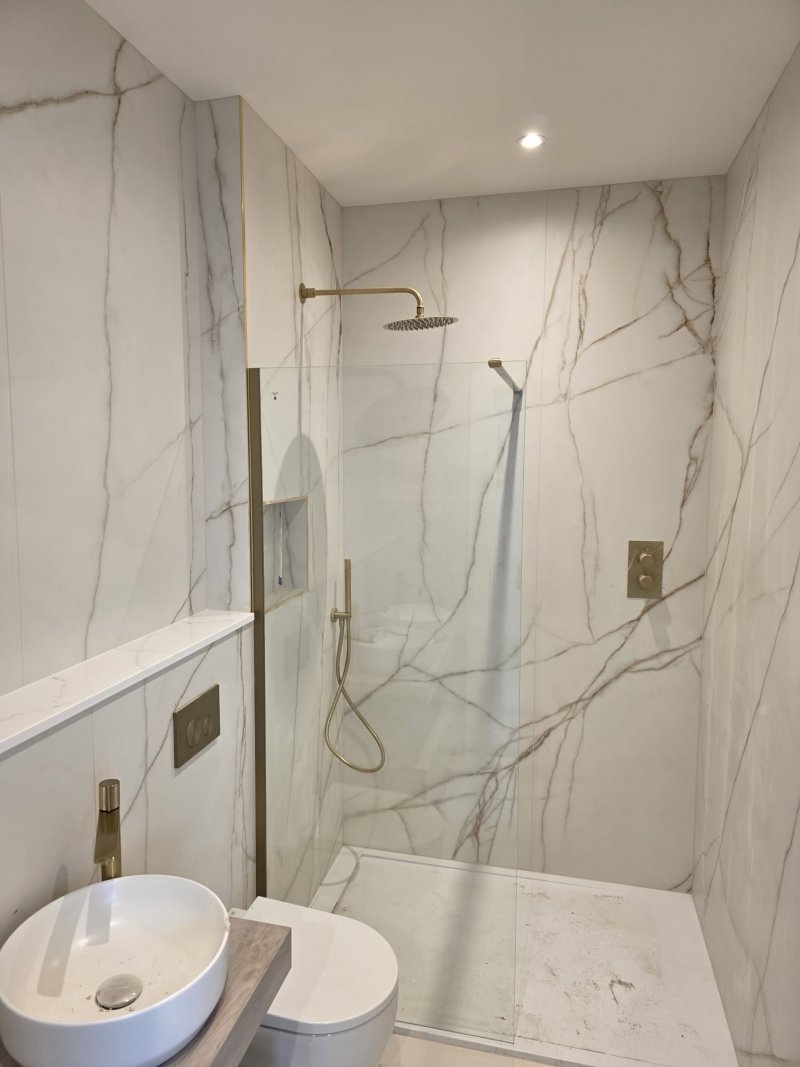 Contemporary marble bathroom with wooden vanity and gold shower fixtures by RC Tiling Dublin