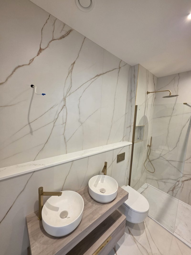 Luxury marble bathroom with double vessel sinks and gold shower fixtures by RC Tiling Dublin