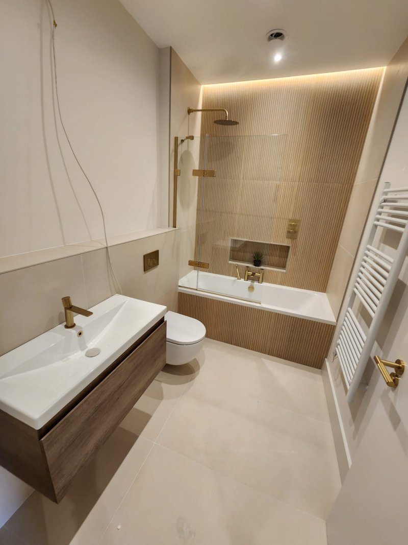 Elegant bathroom with brass shower fixtures and textured wall panel by RC Tiling Dublin