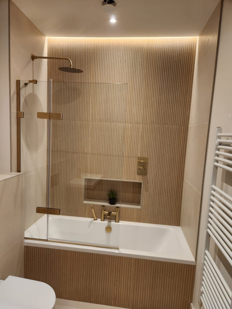 Modern bathroom with gold fixtures and wooden slat wall by RC Tiling Dublin