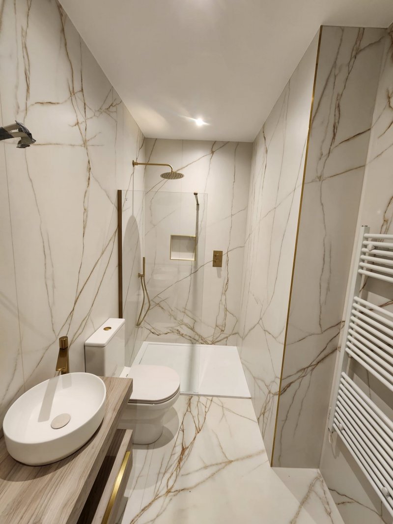 Compact marble bathroom with walk-in shower and gold fixtures