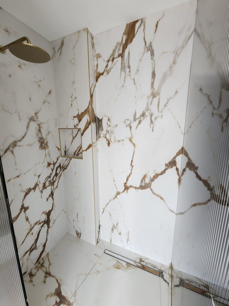 Modern marble shower with gold rain shower and recessed shelf by RC Tiling Dublin
