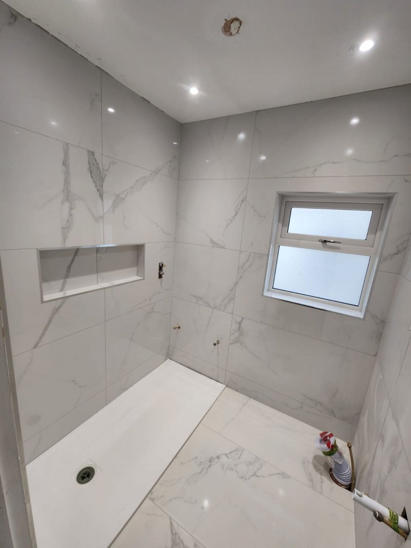 Bathroom shower area with white marble tiles and installed drain – RC Tiling Dublin