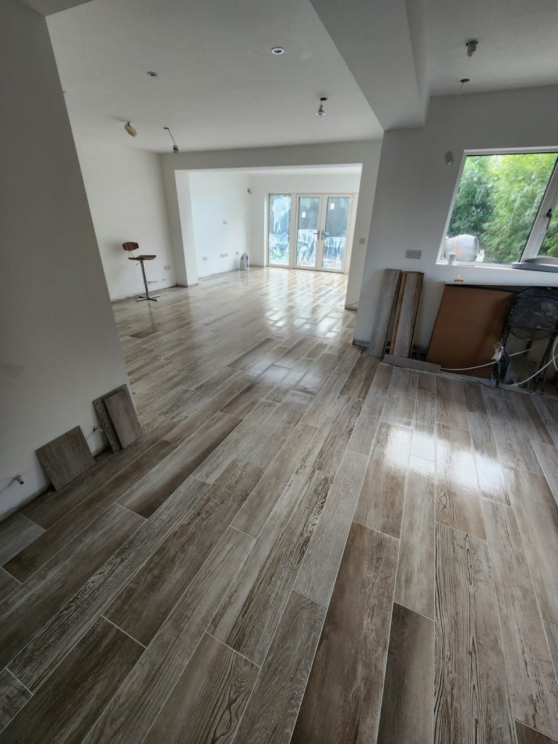 Close-up of seamless wood-effect porcelain floor joint between kitchen and living zones