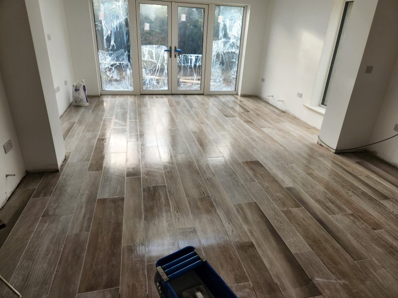 Newly laid, high-gloss wood-effect porcelain floor tiles in a staggered pattern during a home renovation by RCTiling Dublin.