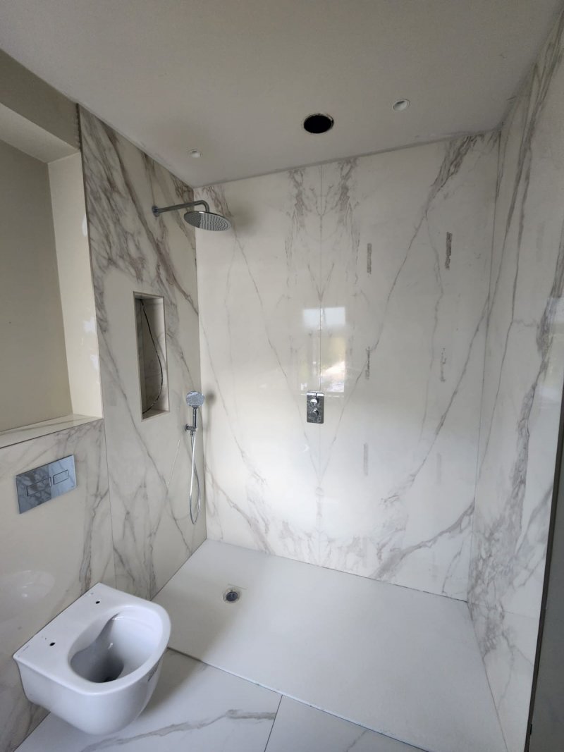 Bathroom with wall-mounted toilet and marble tiles on floor and walls – RC Tiling Dublin