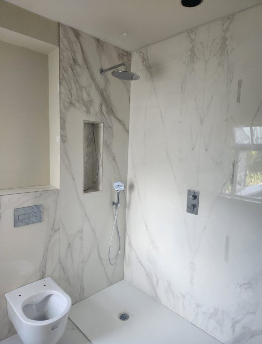Diagonal view of marble shower area with niche and rainfall showerhead – RC Tiling Dublin