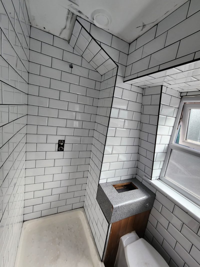 Bathroom view from door with white brick-style ceramic tiles and window above toilet – RC Tiling Dublin
