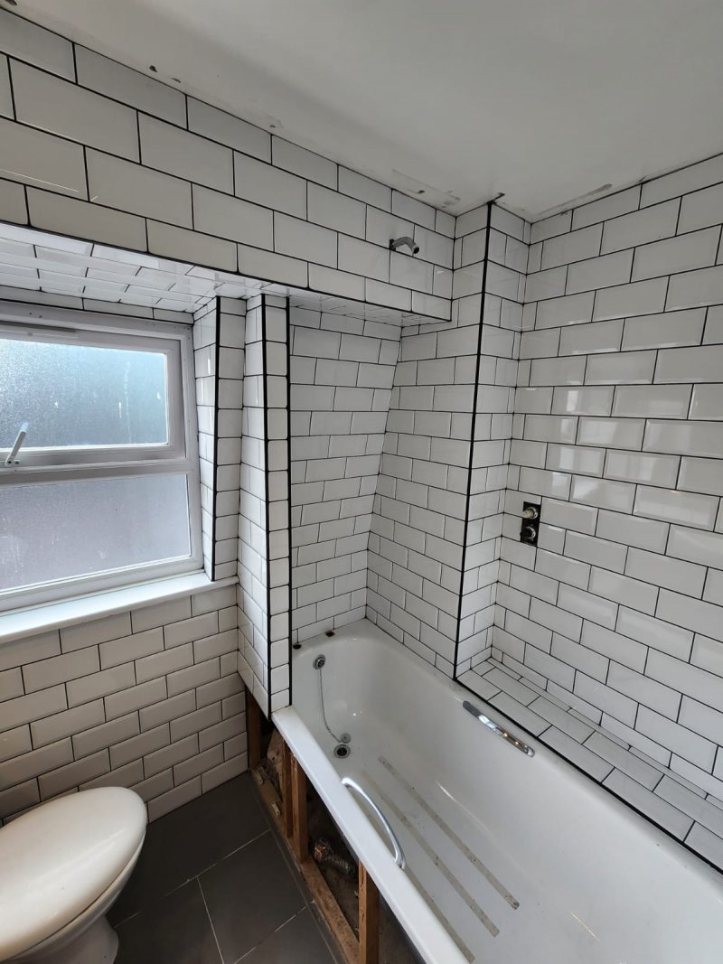 Bathroom view from door with bathtub, toilet, and white ceramic tiles in brick pattern – RC Tiling Dublin