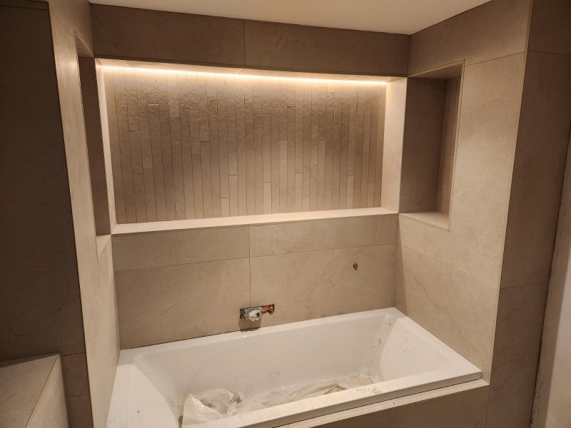 Bathroom renovation with beige ceramic tiles, built-in tub, and illuminated niche – RC Tiling Dublin