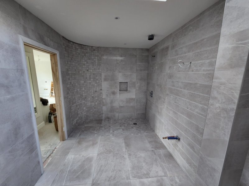 Shower room with large-format grey tiles and mosaic on curved wall and shower floor – RC Tiling Dublin