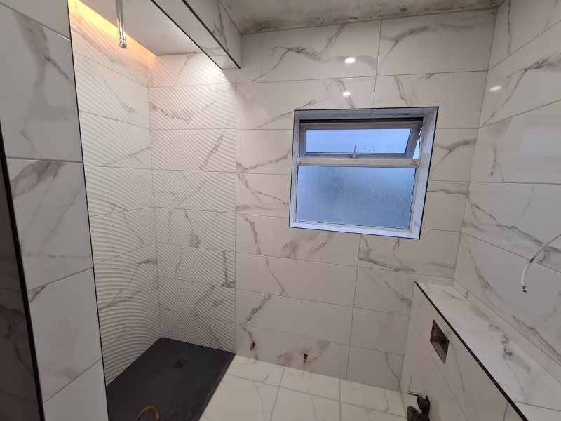 Shower room with marble-effect tiles and dark shower floor – RC Tiling Dublin