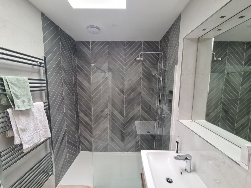 Modern bathroom with chevron shower wall, skylight, and white basin – RC Tiling Dublin