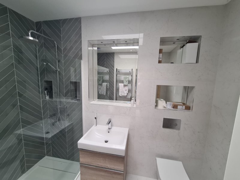 Bathroom with marble-effect wall, built-in shelves, and chevron shower – RC Tiling Dublin