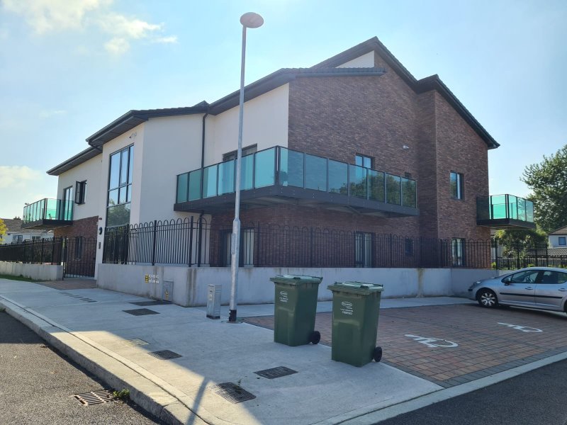 The beautifully completed exterior of a modern Dublin residence, showcasing new glass balconies and a professionally laid block stone paving in the courtyard.