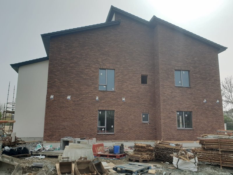 A modern two-story brick and render building in Dublin during the early construction phase, with building materials and scaffolding ready on site.