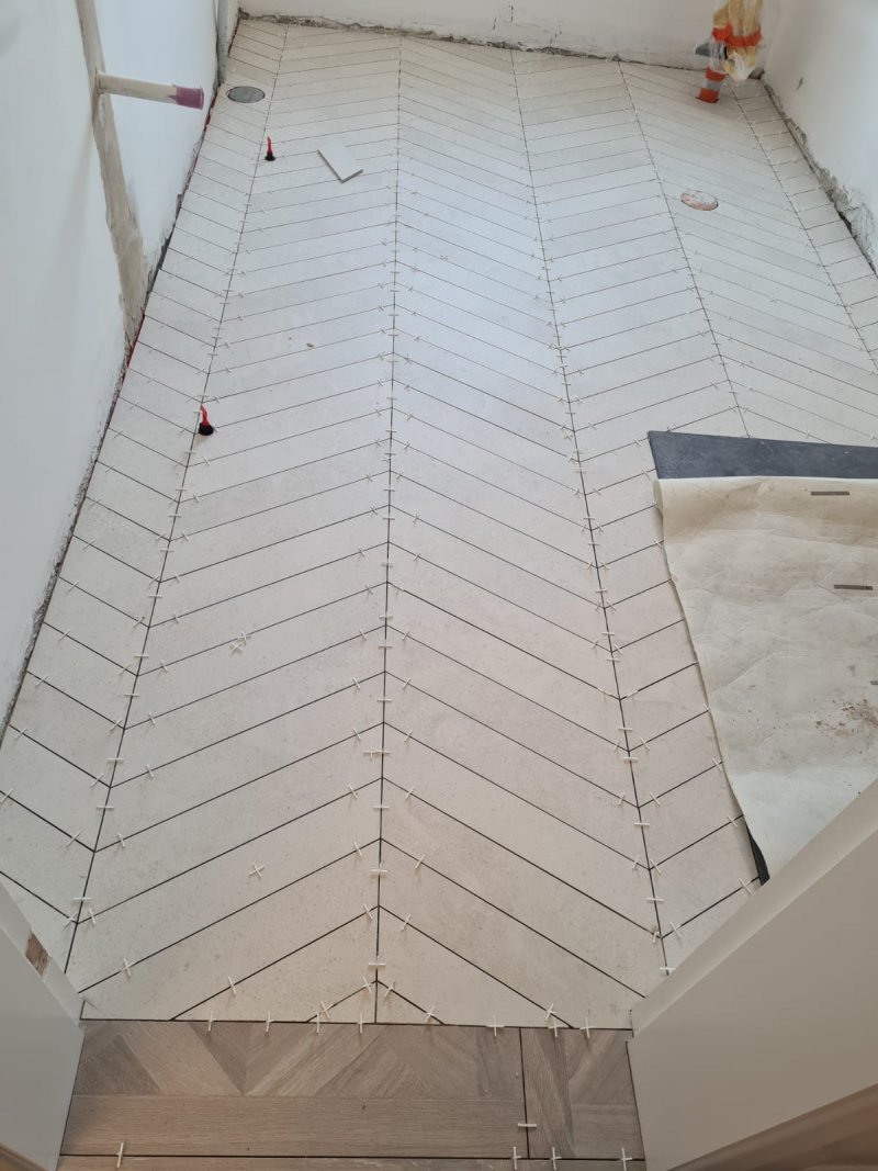 Herringbone tile pattern on bathroom floor with light-colored tiles – RC Tiling Dublin