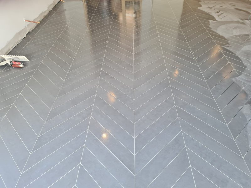 Chevron-pattern tile installation with narrow gray tiles and white grout – RC Tiling Dublin