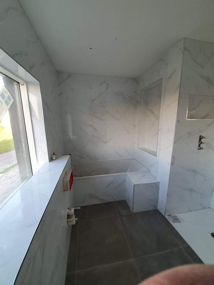 Tiled bathroom niche and bathtub surround with white marble tiles installed by RCTiling Dublin.