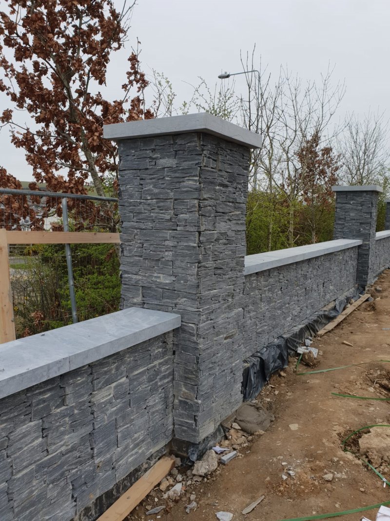 Close-up of grey stone cladding texture on a garden pillar with flat stone cap.