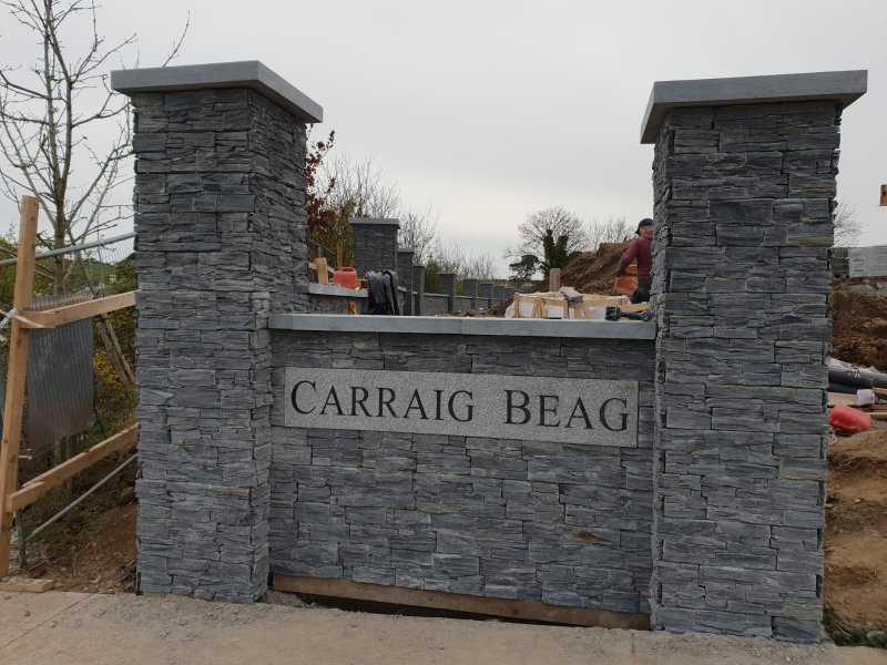 Stone clad estate entrance pillar with Carraig Beag granite sign and limestone capping by RCTiling Dublin.