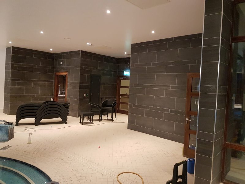 Professional commercial pool tiling in Dublin featuring large-format dark grey wall tiles and blue mosaic spa steps by RCTiling.