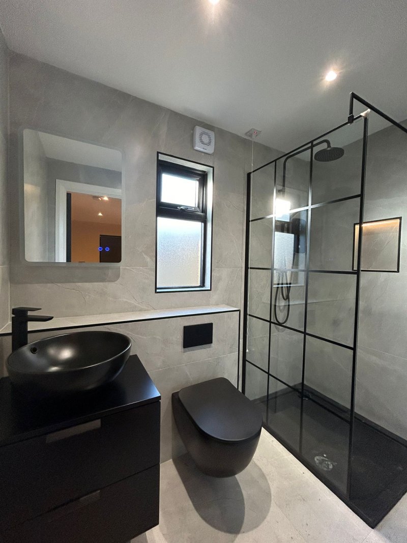 Modern bathroom with black-framed shower and wall-mounted black toilet by RC Tiling Dublin
